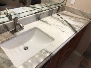 Ceramic rectangular white vanity sink integrated into a granite countertop with a modern faucet, ideal for bathroom or kitchen settings.