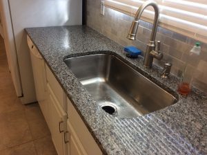 Stainless steel single bowl kitchen sink with faucet and granite countertop, ideal for modern kitchens and home renovations.
