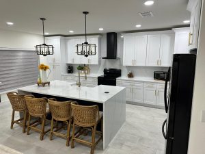 Calacatta Athena quartz countertop in a modern kitchen with white cabinetry and bar seating, featuring pendant lighting and stainless appliances.
