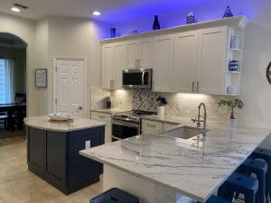 Contemporary kitchen featuring pearl white cabinets, imperial blue island, and Giotto quartzite countertops with full backsplash tiles.