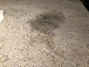 Granite kitchen worktop showing a noticeable stain on the surface, highlighting maintenance needs for quartz and granite countertops.